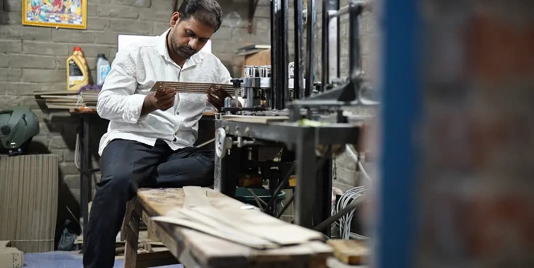 Tailor sits at a sewing machine, examining a piece of fabric